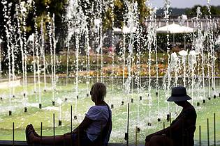 Michael Reichel/dpa | Zwei Frauen sitzen an einem Springbrunnen im egapark in Erfurt in Thüringen.
