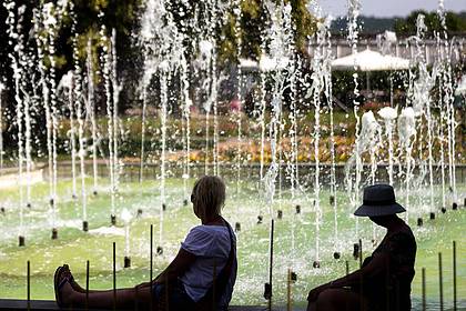 Michael Reichel/dpa | Zwei Frauen sitzen an einem Springbrunnen im egapark in Erfurt in Thüringen.