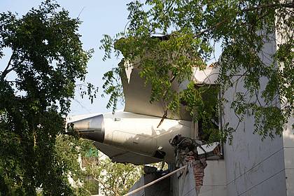 Ajit Solanki/AP/dpa | Trümmer des Flugzeugs ragen aus einem Gebäude.